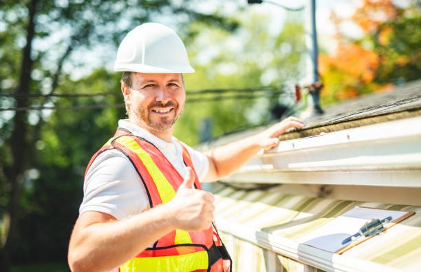 A man with hard hat standing on steps inspecting roof